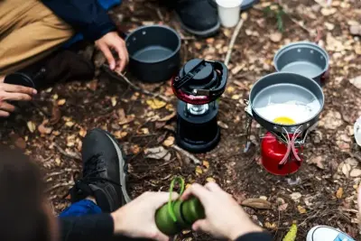 Personer der sidder ved en Trangia og laver mad i naturen